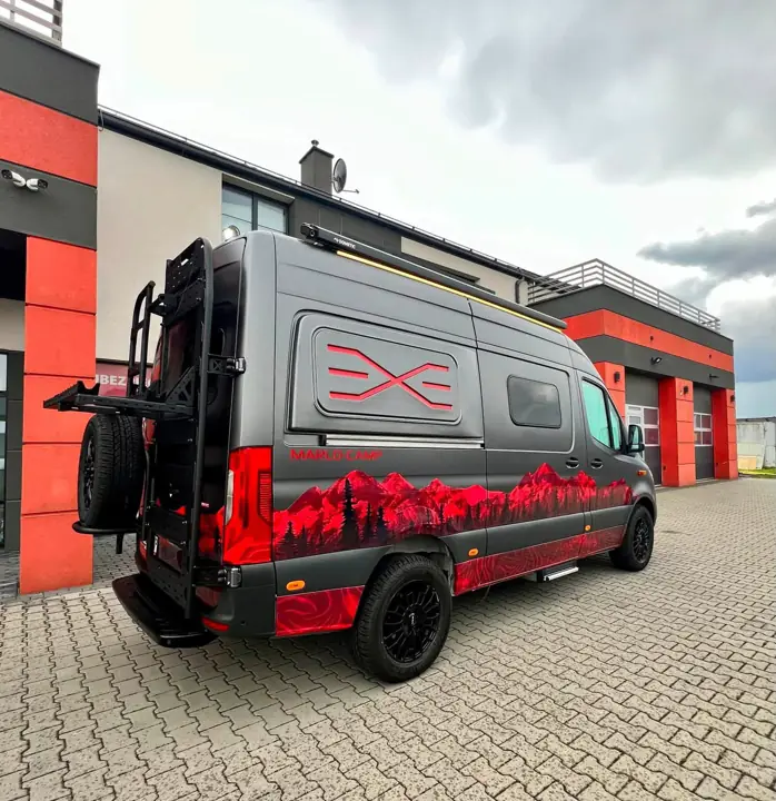 Mercedes Sprinter po zabudowie – grafitowo-czerwone oklejenie, drabinka i koło zapasowe na tylnych drzwiach