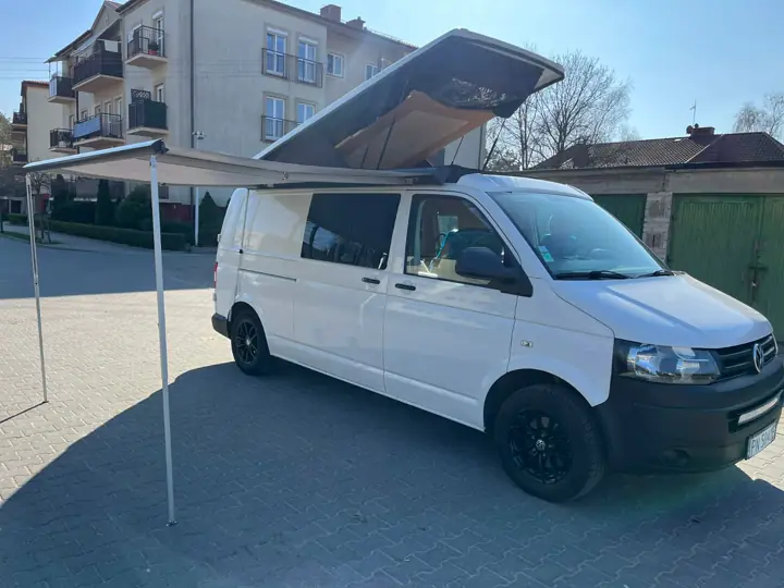 Biały VW T5 z otwartym dachem podnoszonym i rozłożoną markizą