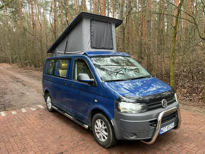 Niebieski VW T5 z dachem podnoszonym w lesie