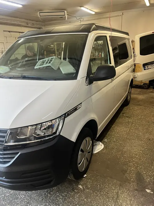 Biały VW T6.1 z dachem podnoszonym w warsztacie