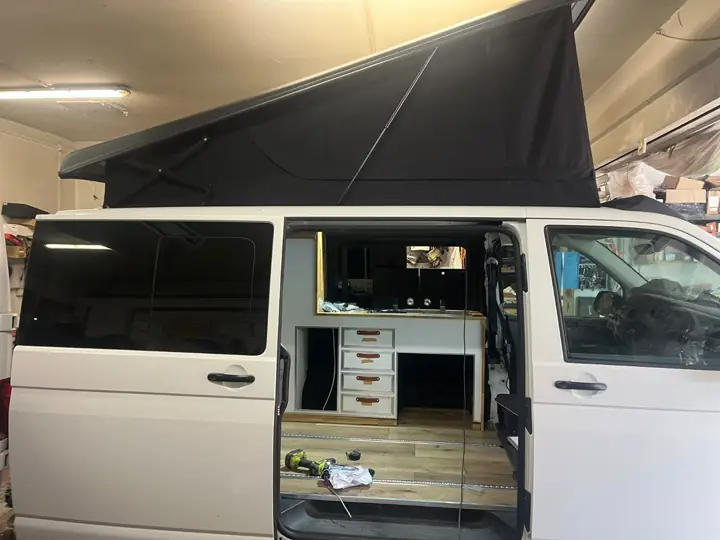Biały VW T6 z rozłożonym dachem i otwartymi drzwiami, widoczna zabudowa kuchenna