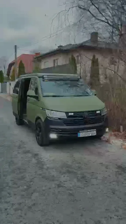 Film: zielony van terenowy z kołem zapasowym na tylnych drzwiach i zabudową z oknem